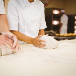 two people kneading bread