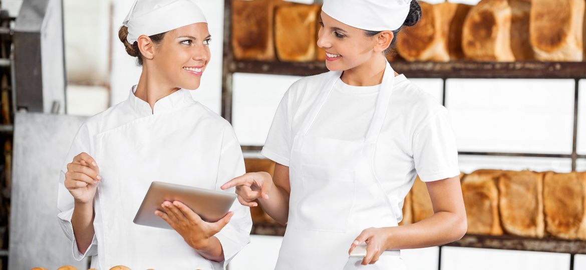 two women bakery chefs looking at tablet